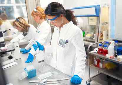 Photo of three real female scientists researching in laboratory. Photo taken behind the glass.